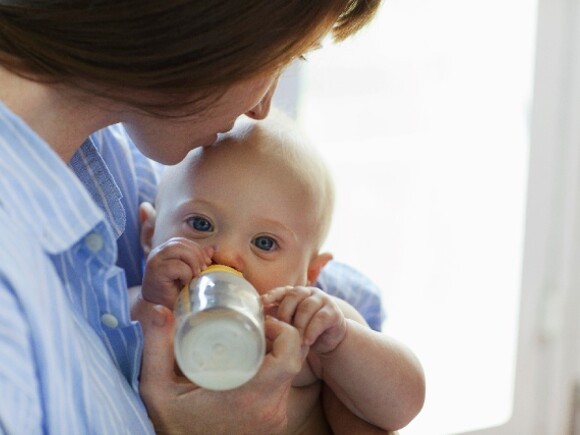 Bébé boit son biberon avec des légumes